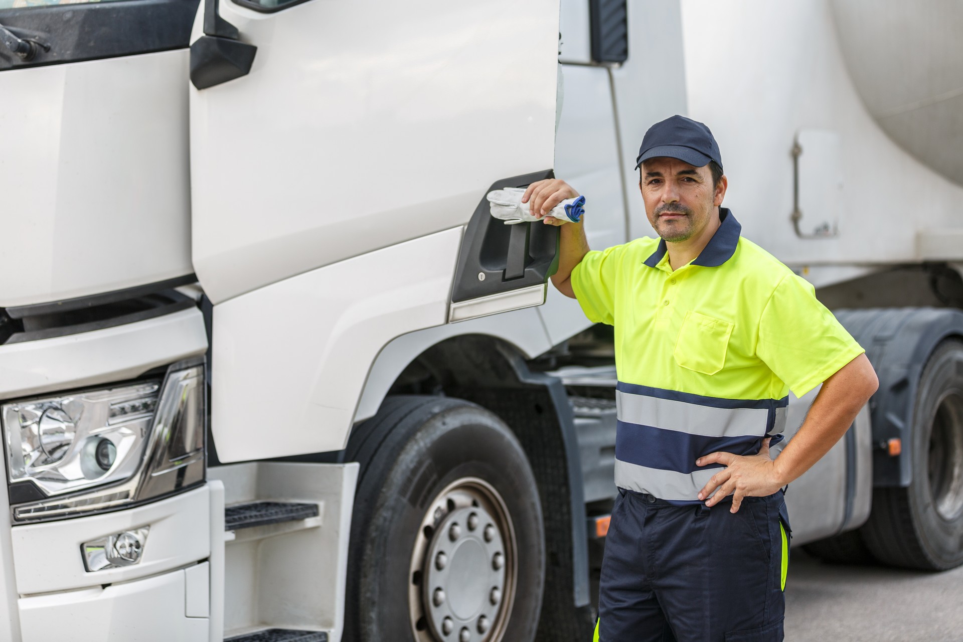 Male truck driver standing by door of vehicle while looking at camera